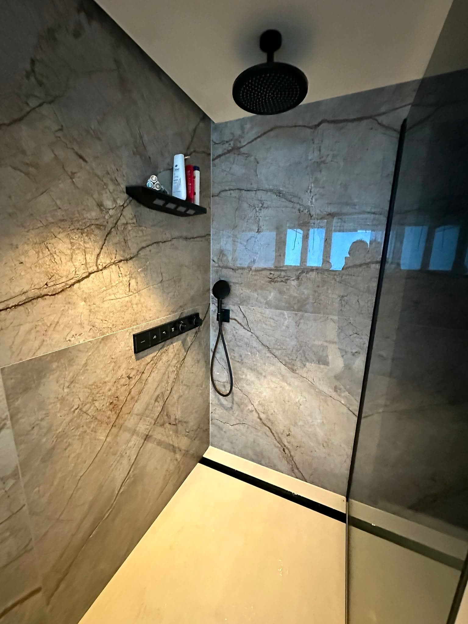Douche met donkere kranen en grootformaat steenlook wandpanelen