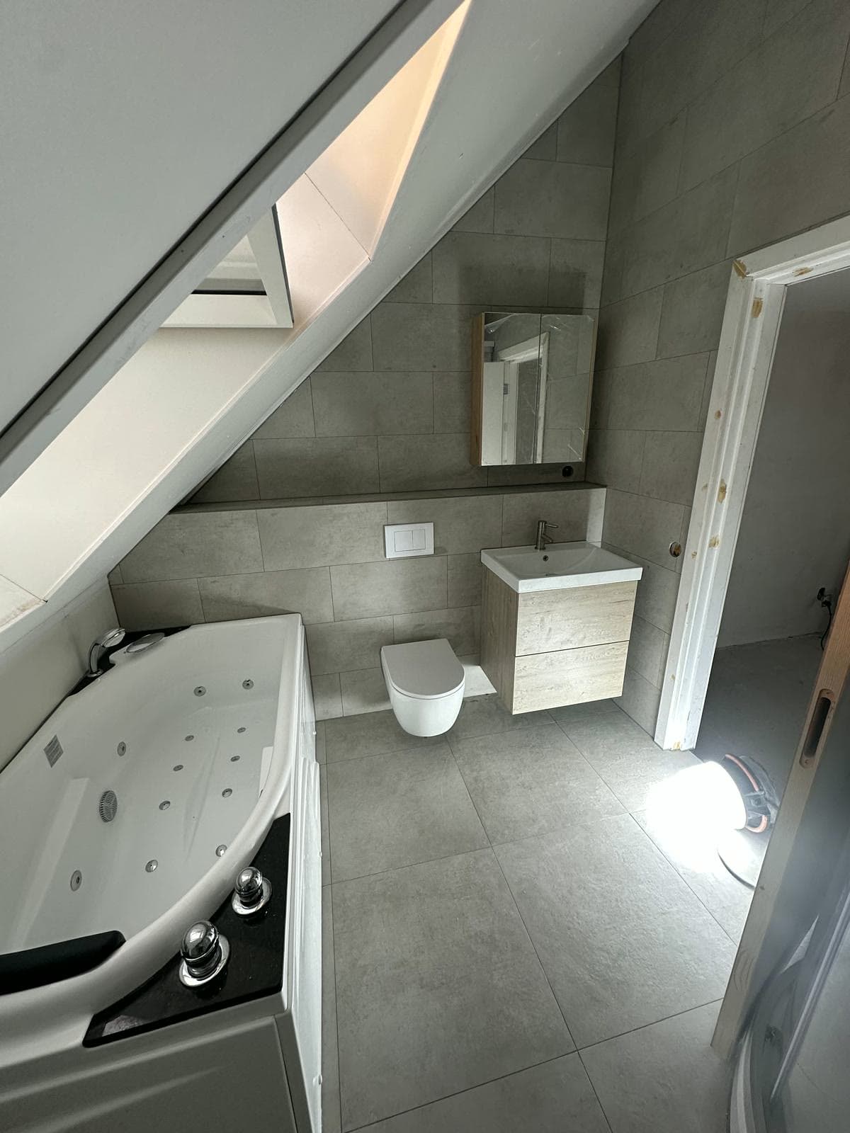 Nieuwe badkamer onder het schuine dak met bad en wandtoilet