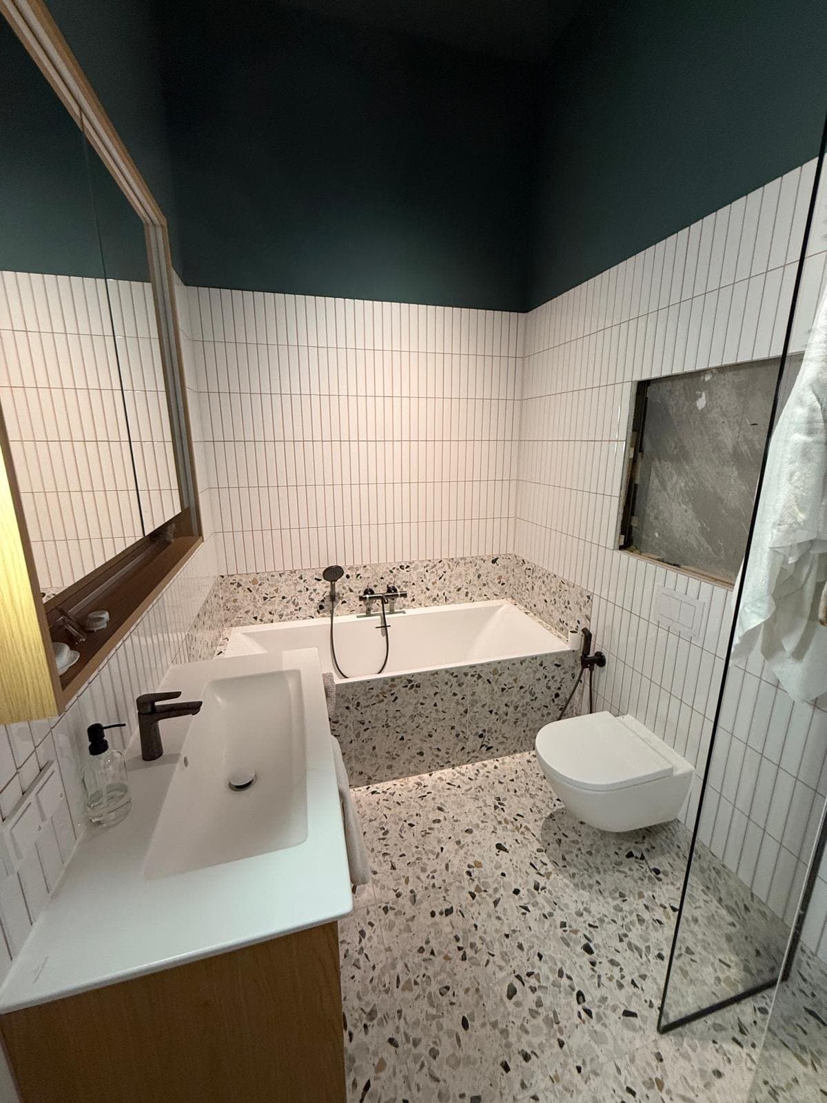Bad en wandcloset met witte staaftegels en zwarte inbouwkranen