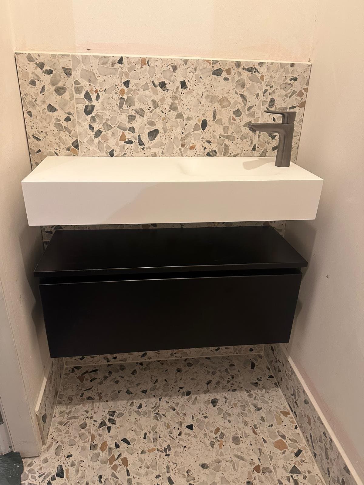 Apart toilet met fonteinmeubel en terrazzo achterwand