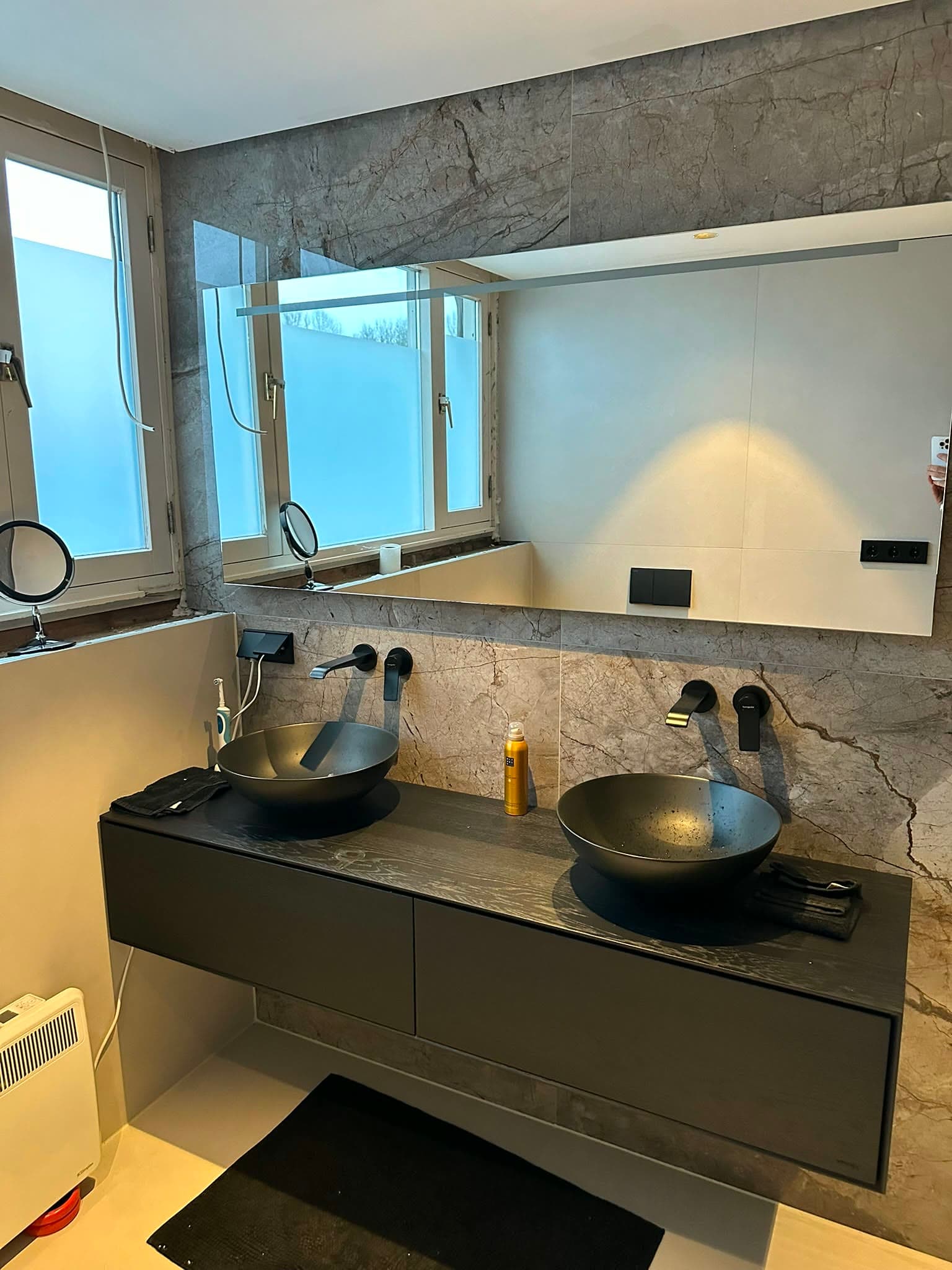Afgewerkte badkamer met donkere glazen douchewand, inbouwverlichting en grootformaat wandpanelen
