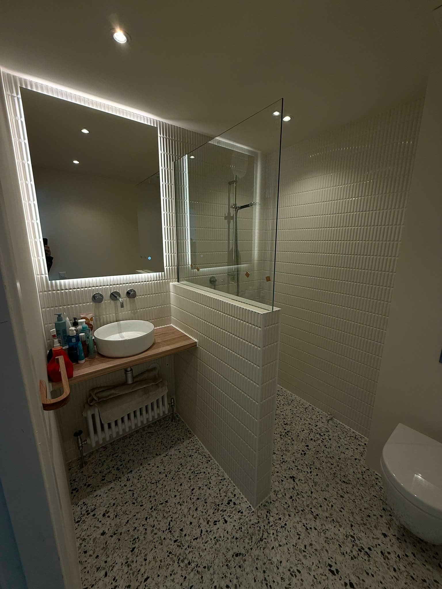 Gerenoveerde badkamer in Amsterdam met glazen douchewand en lichte reliëftegels